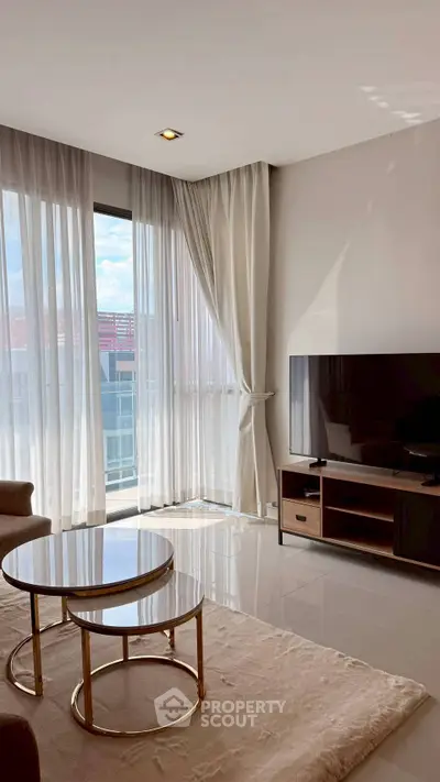 Elegant living room with large windows, modern furniture, and natural light.
