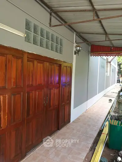 Charming exterior with wooden doors and covered walkway, perfect for tropical living.
