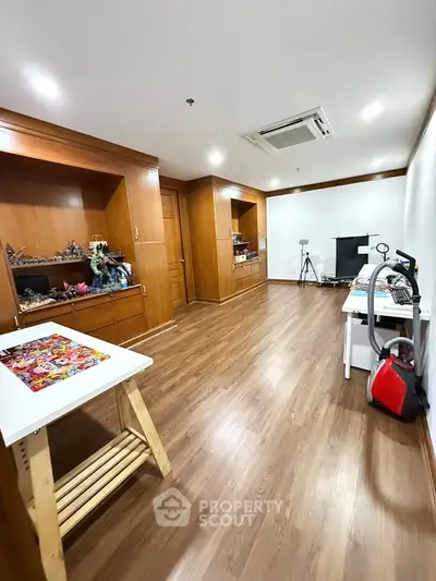 Spacious study room with wooden flooring and built-in shelves, perfect for a home office or creative space.