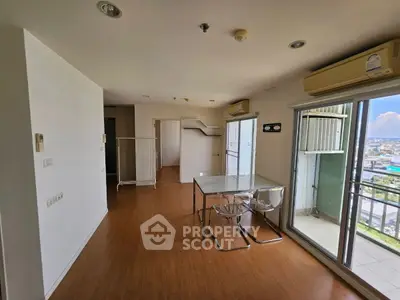 Spacious modern living room with balcony and city view, featuring sleek glass dining table and chairs.