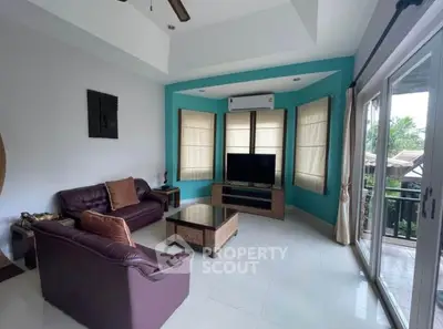 Spacious living room with modern decor and large windows opening to a balcony view.