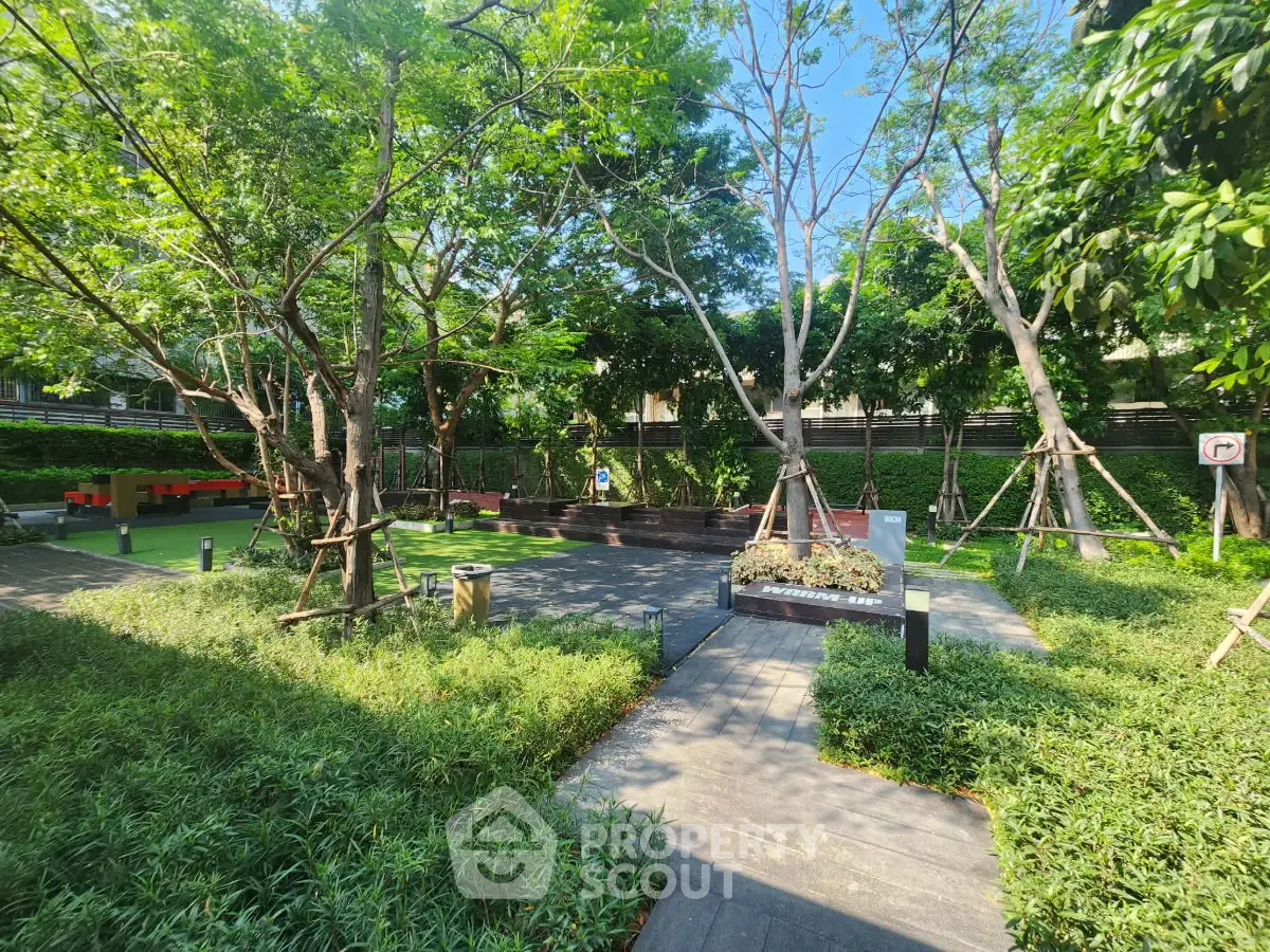 Lush green garden area with trees and pathways in a residential complex.