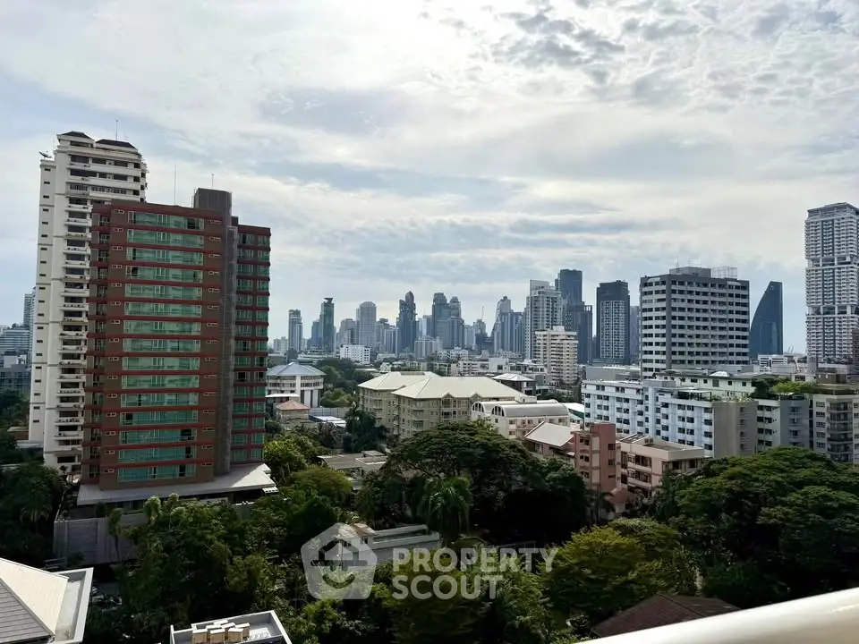 Stunning cityscape view from a high-rise balcony showcasing urban skyline and lush greenery.