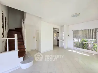 Spacious open-plan living area with staircase and large windows