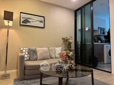 Modern living room with cozy sofa, elegant decor, and view into a sleek kitchen area.