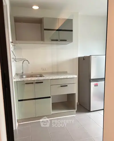 Modern kitchen with sleek cabinetry and stainless steel fridge in a compact layout.