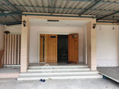 Charming entrance of a cozy home with inviting wooden doors and sheltered porch.