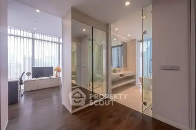 Modern apartment interior with glass partitions and wooden flooring, featuring a stylish living area and bathroom.