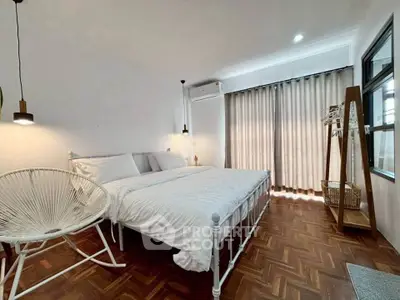 Spacious bedroom with twin beds and modern decor, featuring parquet flooring and ample natural light.