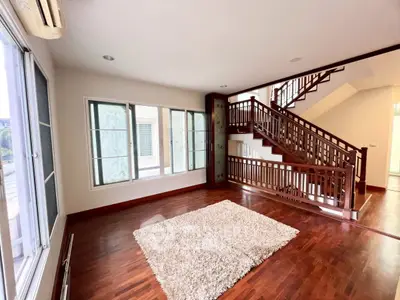 Spacious living room with wooden floors and elegant staircase