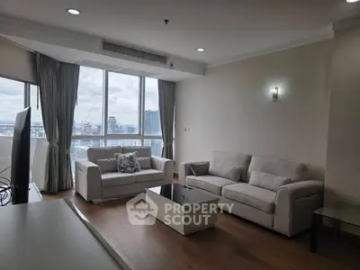 Spacious living room with large windows and modern furniture in a high-rise apartment.