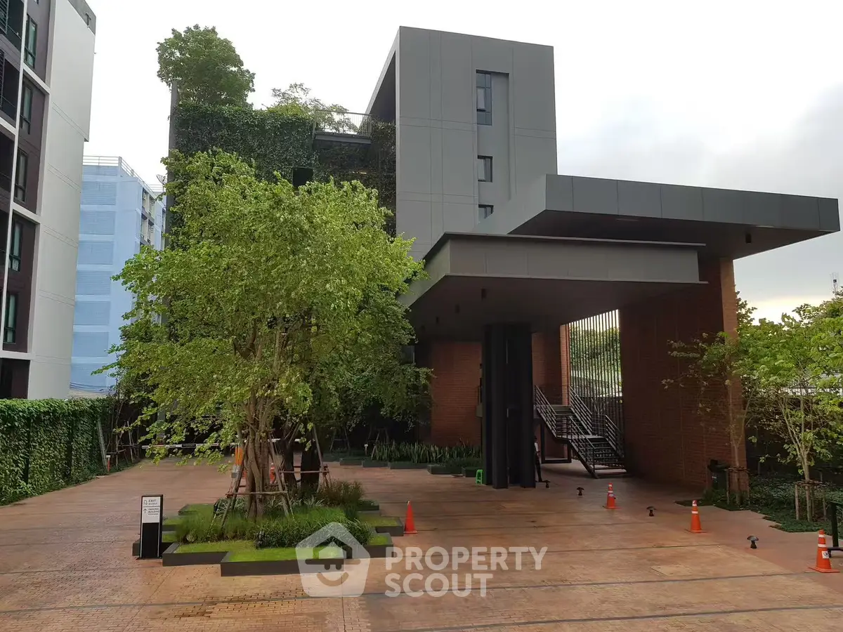 Modern building entrance with lush greenery and sleek architecture