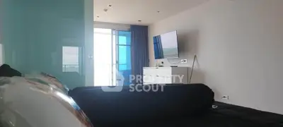 Modern living room with sleek TV setup and balcony view in a stylish apartment.