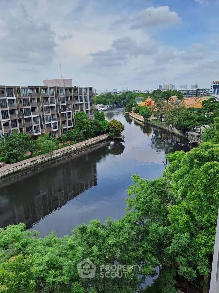 Stunning river view from a modern apartment balcony with lush greenery and cityscape.