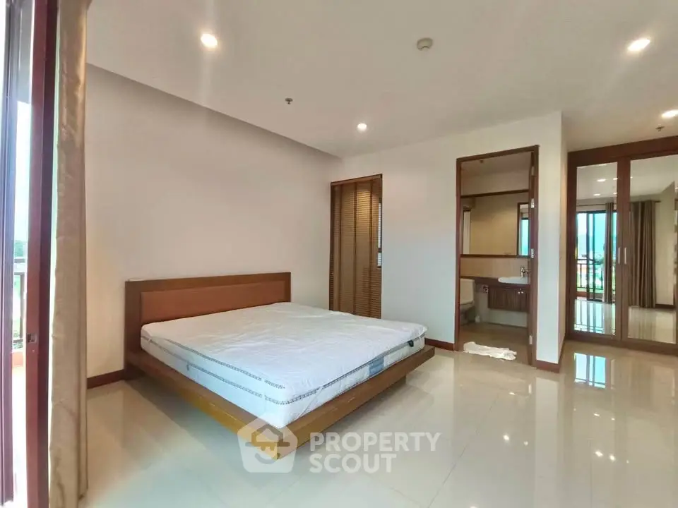 Spacious bedroom with modern design and large windows offering natural light.