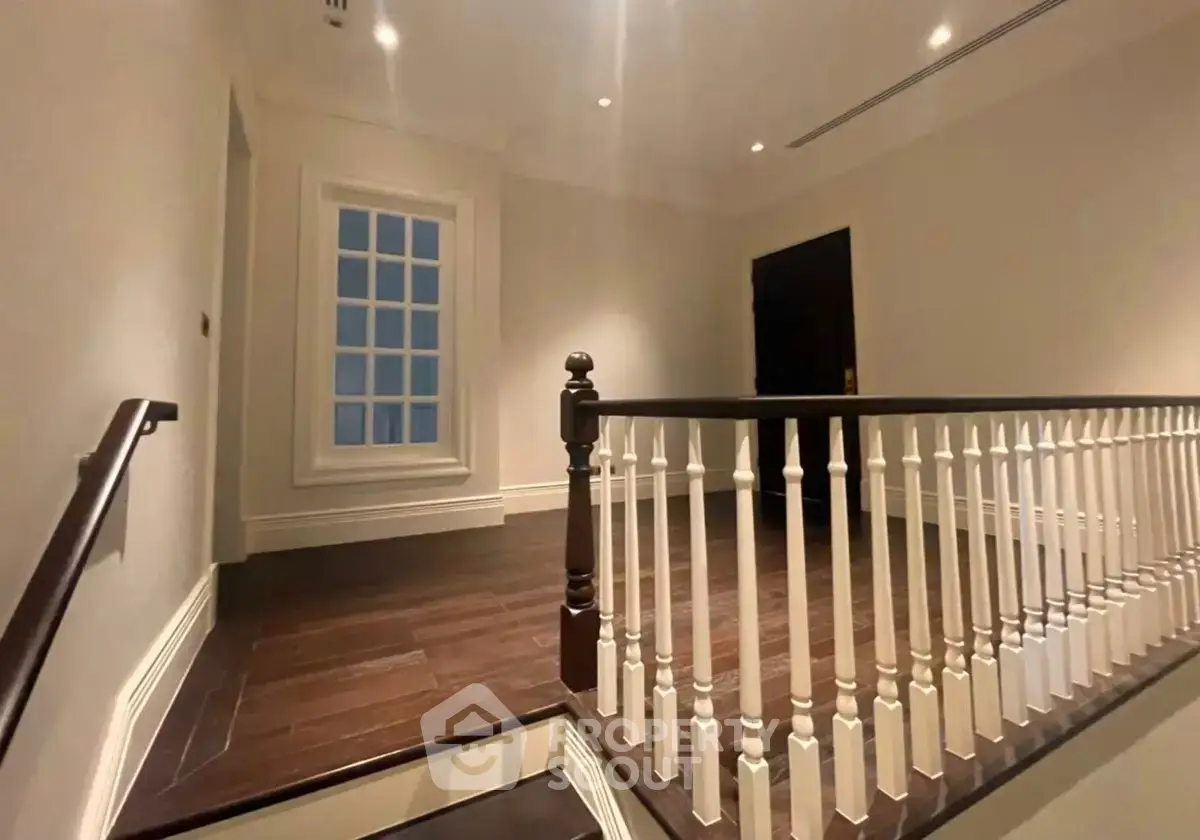 Elegant interior staircase with wooden flooring and classic railing design.