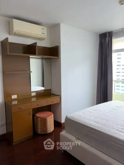 Spacious bedroom with modern furniture and natural light in a high-rise apartment.