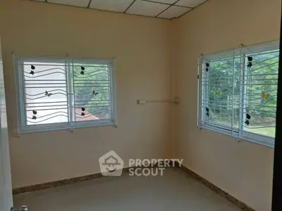 Bright empty room with two windows and garden view, ideal for customization.