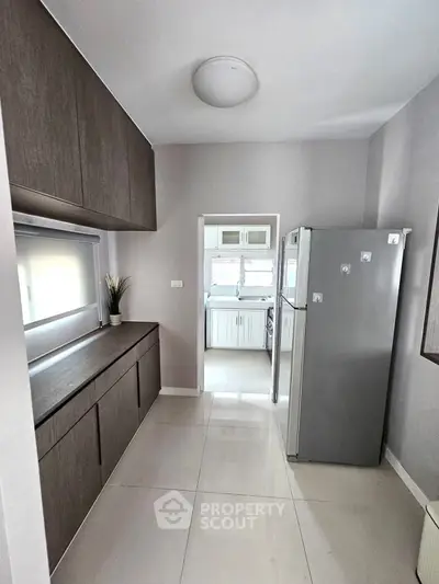Modern kitchen with sleek cabinets and stainless steel fridge in bright, minimalist design.
