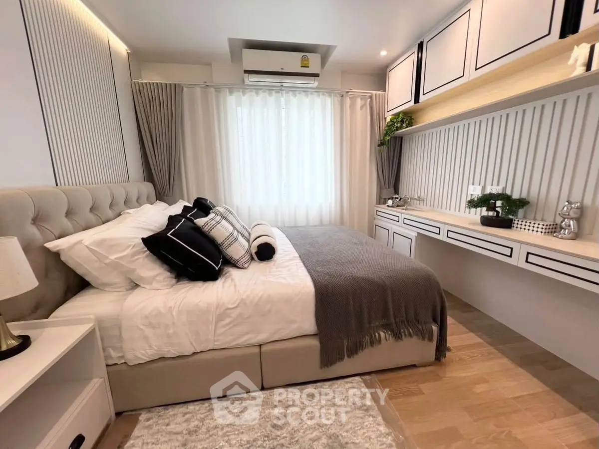 Luxurious bedroom with elegant decor and ample natural light, featuring stylish built-in storage and plush bedding.