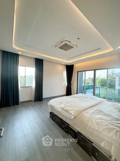 Spacious modern bedroom with large windows and elegant ceiling design