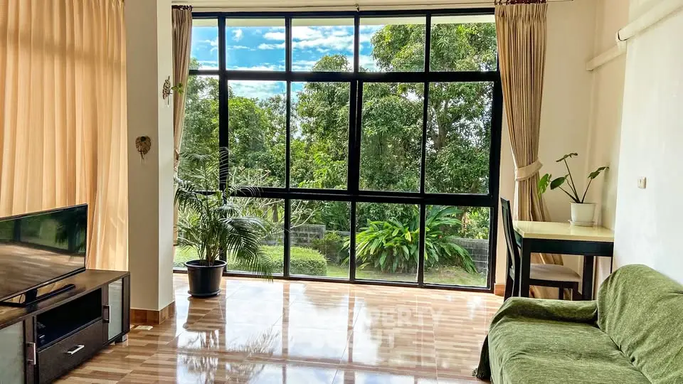 Spacious living room with large windows and garden view, perfect for relaxation.