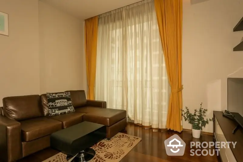 Cozy living room with warm lighting, featuring a comfortable brown leather sofa, elegant drapery, and sleek hardwood flooring for a welcoming ambiance.