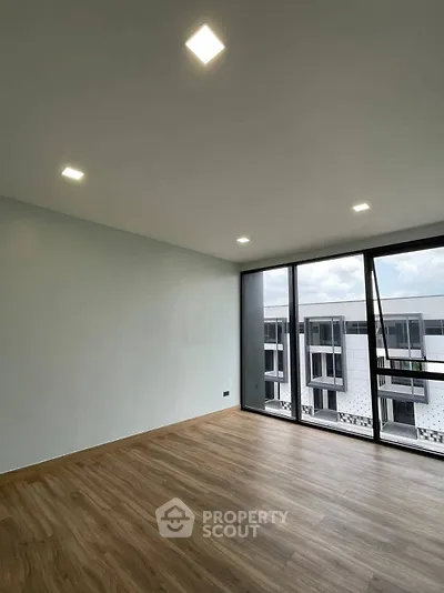 Spacious modern living room with large windows and wooden flooring, offering a bright and airy atmosphere.