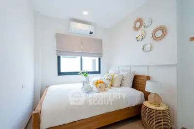 Cozy bedroom with stylish decor and natural light, featuring a comfortable bed and modern air conditioning.