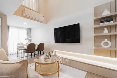 Modern living room with stylish decor and open dining area, featuring a wall-mounted TV and elegant shelving.