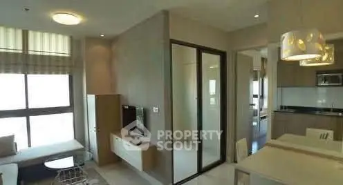 Modern open-plan living room with kitchen, featuring sleek design and ample natural light.