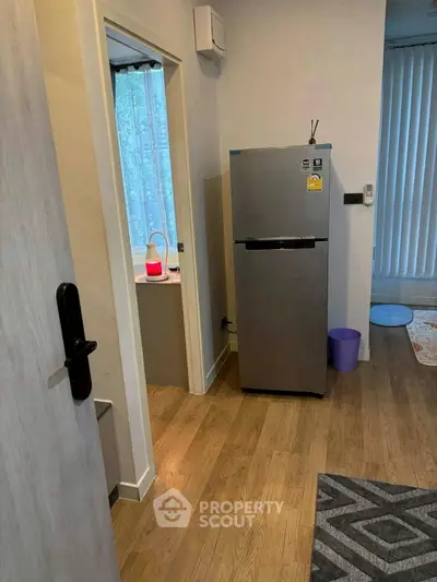 Cozy interior with modern fridge and wooden flooring, perfect for compact living spaces.