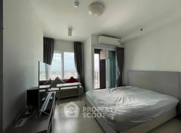 Modern bedroom with balcony and city view, featuring sleek furniture and natural light.