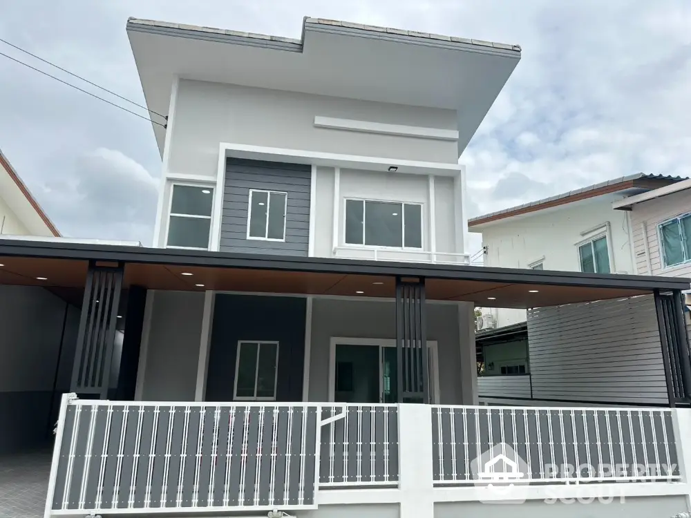 Modern two-story house with sleek design and spacious balcony in suburban neighborhood.