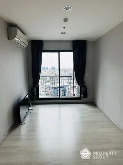 Spacious empty living room with city view and large window, ideal for customization.