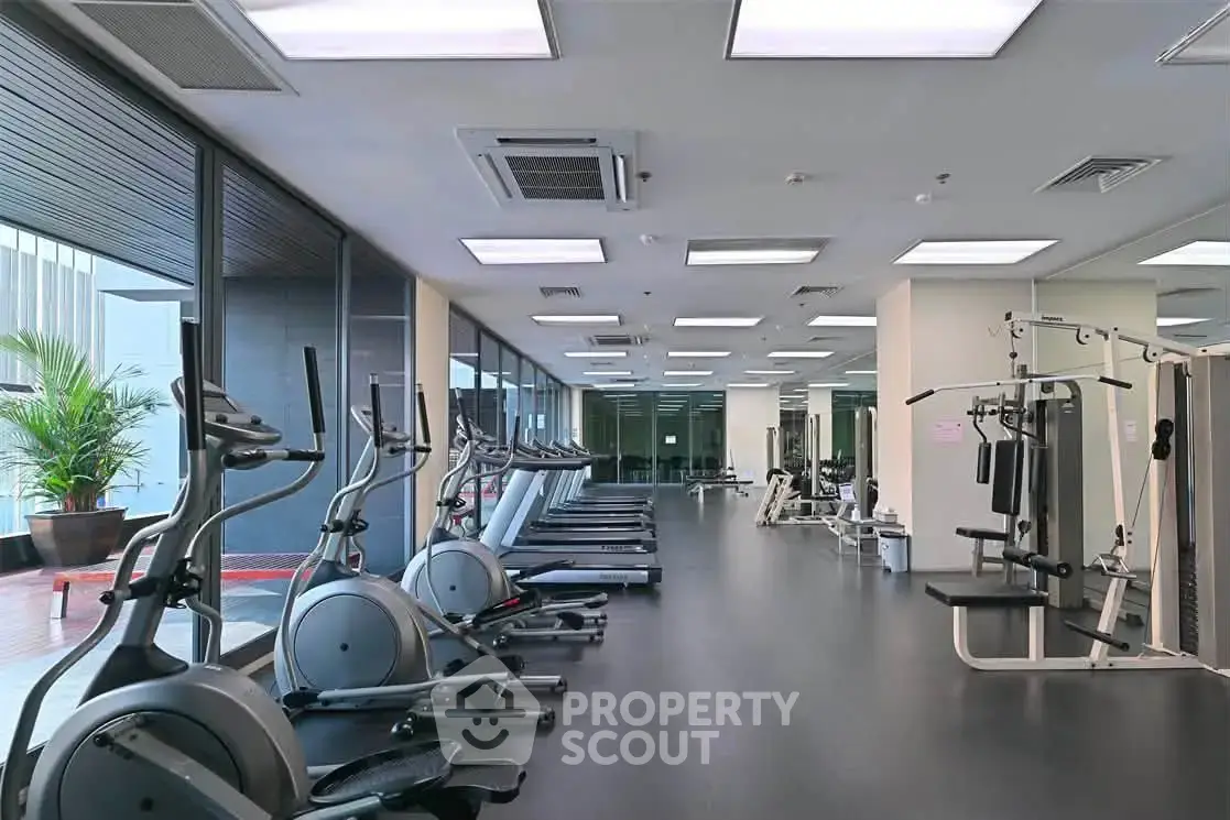 Spacious modern gym with state-of-the-art equipment and large windows for natural light.