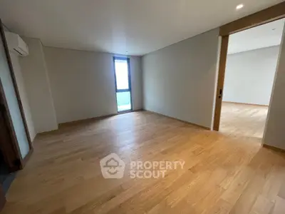 Spacious empty room with wooden flooring and natural light, ideal for customization.