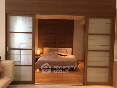 Modern bedroom with sliding doors and wooden accents, featuring a cozy bed and ambient lighting.