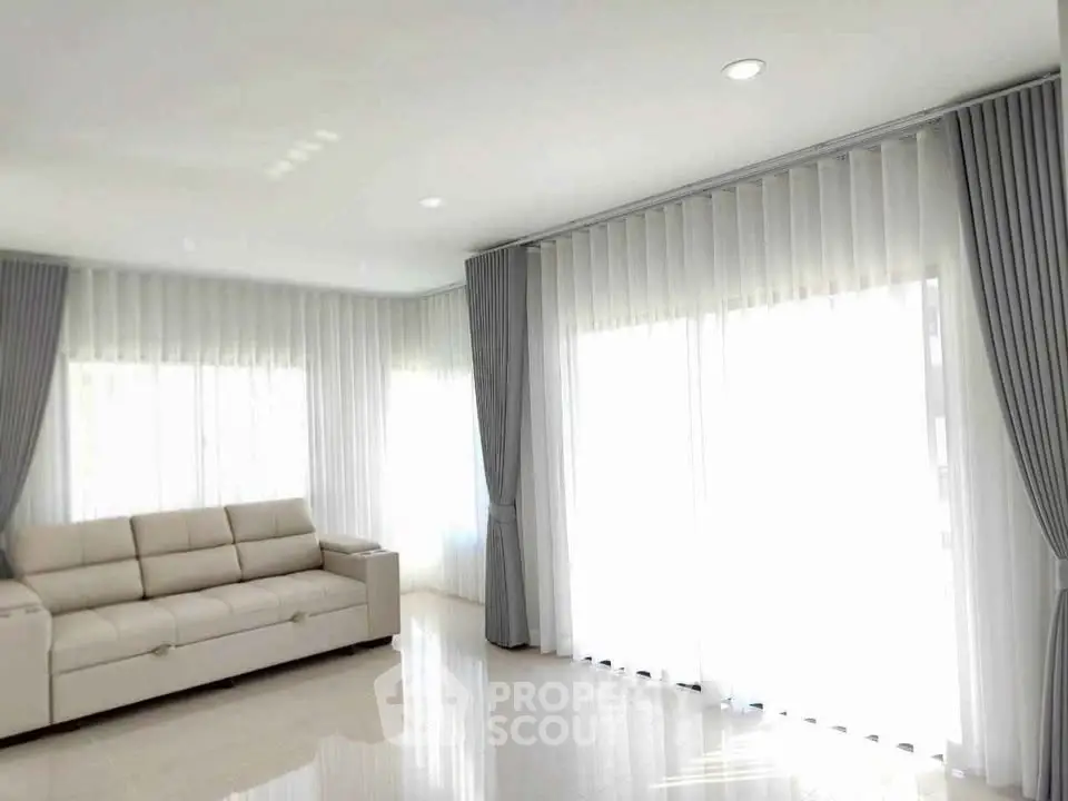 Spacious living room with elegant curtains and modern sofa, flooded with natural light.