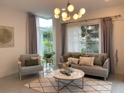Elegant living room with modern decor and large windows offering garden views.