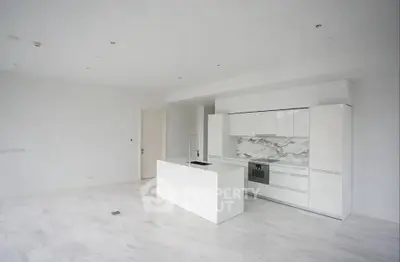 Spacious modern kitchen with sleek white cabinetry and marble backsplash in open layout.