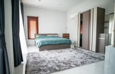 Spacious master bedroom with large bed, plush area rug, ample natural light, and modern wardrobe, perfect for a luxurious living experience.