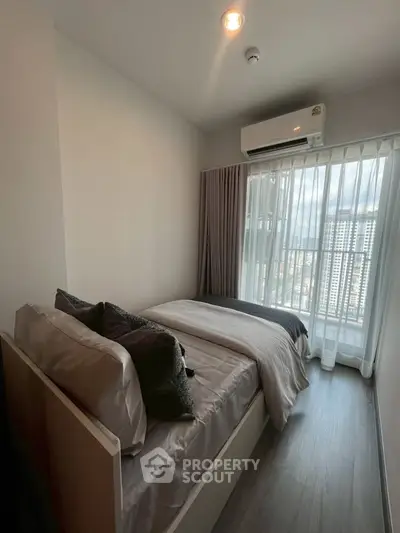 Cozy bedroom with city view and modern air conditioning unit, perfect for urban living.