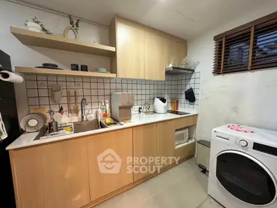 Modern kitchen with wooden cabinets and washing machine, featuring open shelving and sleek design.