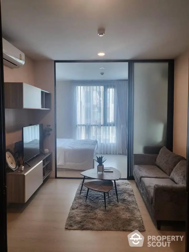 Modern living room with cozy sofa and stylish decor adjacent to a bright bedroom.