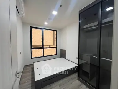 Modern minimalist bedroom with large window and sleek wardrobe in a stylish apartment.