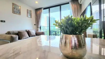 Modern living room with large windows and city view, featuring elegant decor and cozy seating.