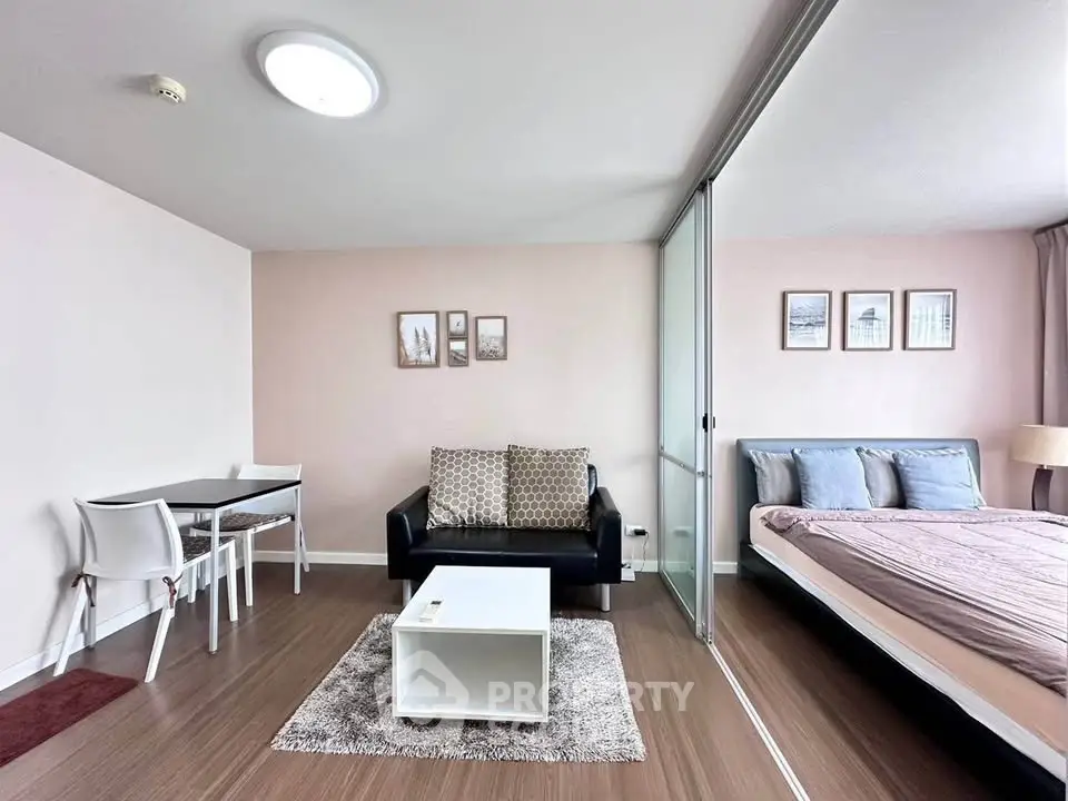 Modern studio apartment with cozy living area and bedroom separated by glass partition.