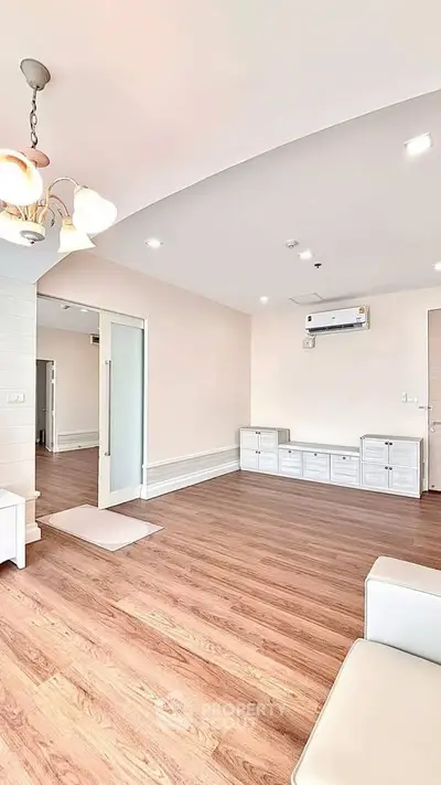 Spacious modern living room with wooden flooring and elegant lighting, perfect for family gatherings.