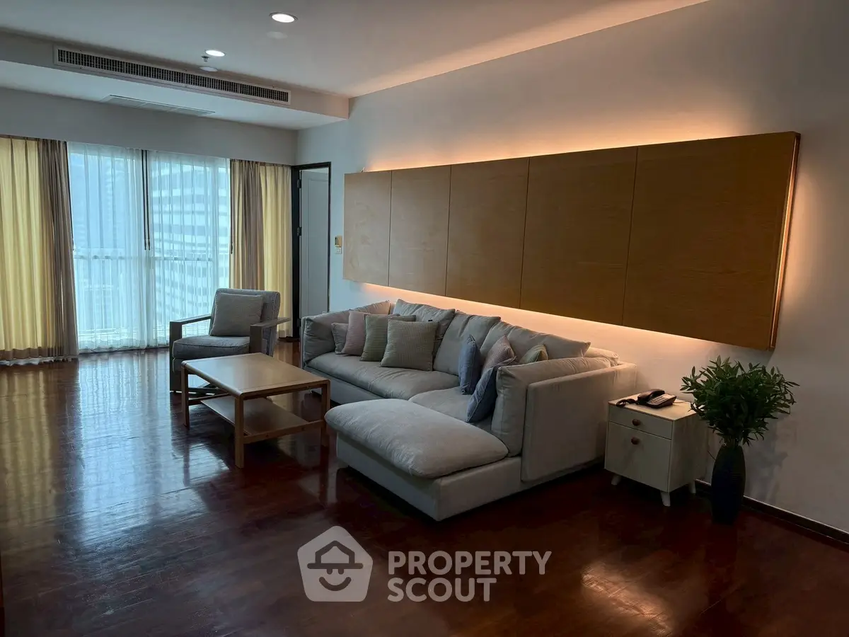 Spacious living room with modern furniture and large windows offering city views.